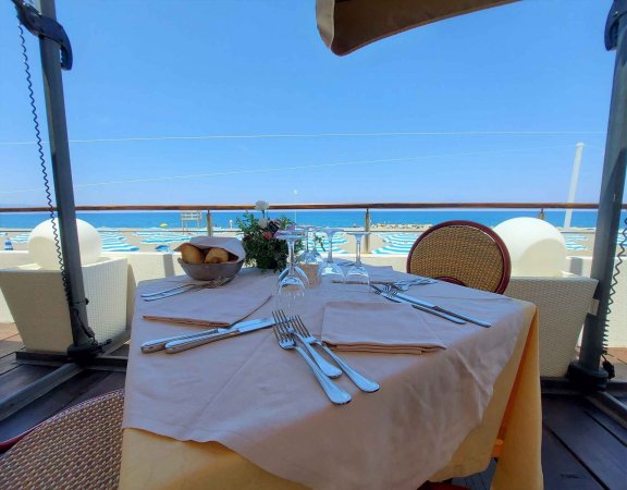 Tavola apparecchiata all'aperto con vista mare.