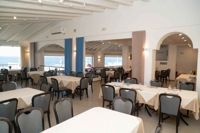 Sala ristorante spaziosa con tavoli bianchi.