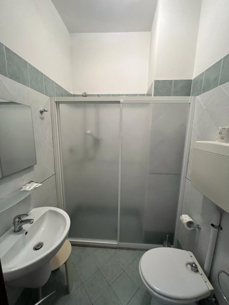 Un bagno con doccia, WC e lavabo con specchio.