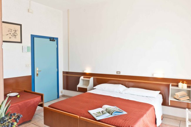 Camera da letto con letto matrimoniale, copriletto rosso e porta blu.