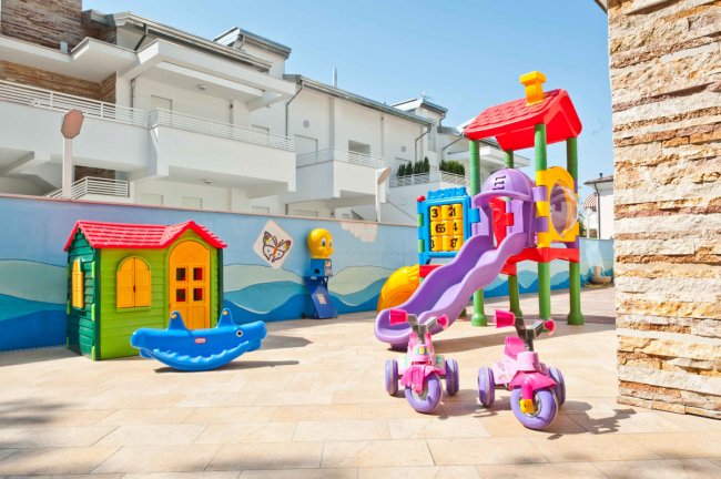 Parco giochi colorato con scivolo e casetta.