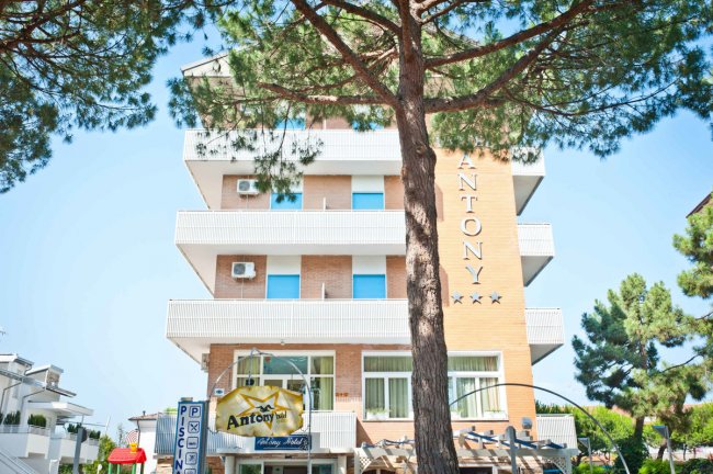 Edificio a più piani con balconi e albero.