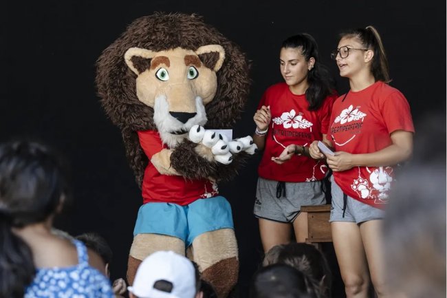 Persona in costume di leone con animatori.