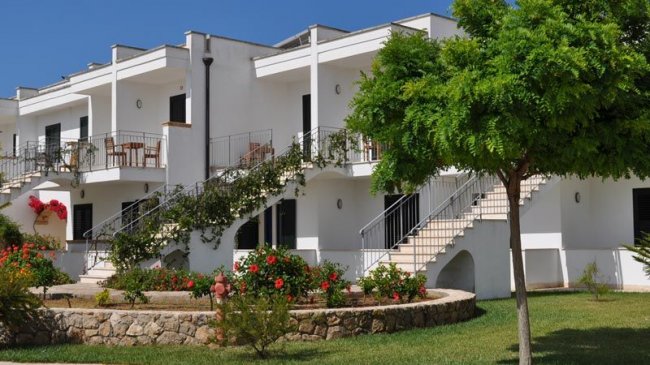 Edificio bianco con balconi e fiori colorati.