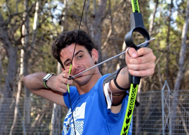 Uomo che tende un arco all'aperto.