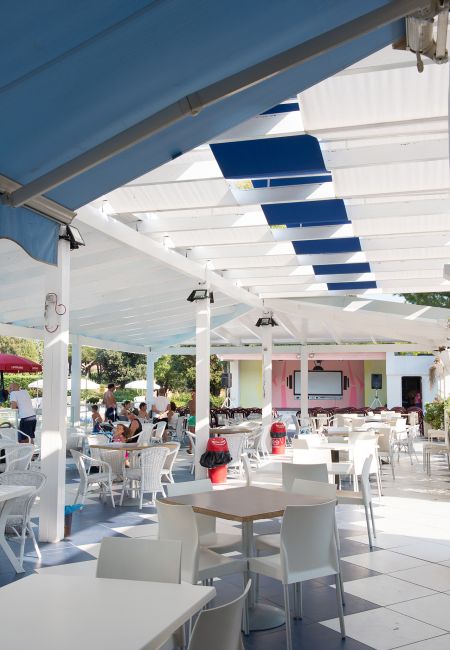 Un patio coperto con tavoli e sedie bianche.