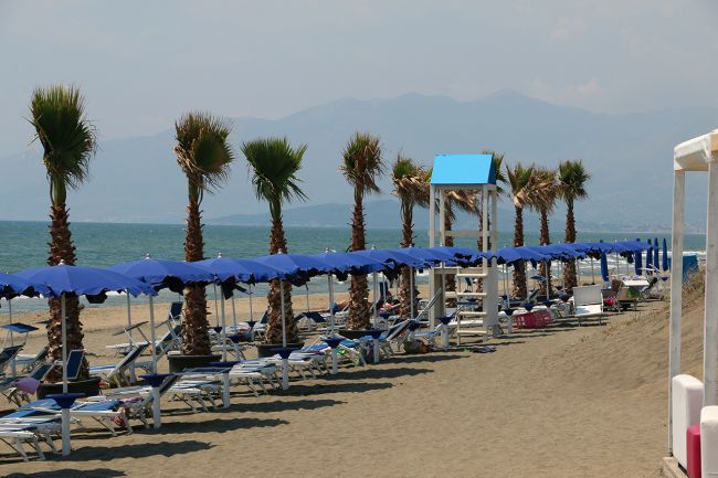 Spiaggia con lettini e ombrelloni blu.