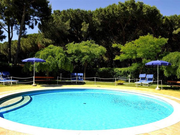 Piscina tonda con lettini e ombrelloni blu.
