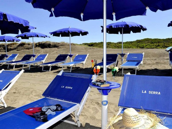 Sedie a sdraio blu su una spiaggia con ombrelloni coordinati.