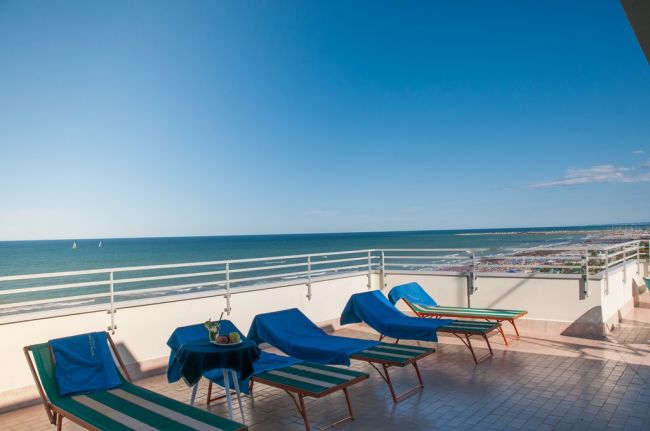 Lettini blu su terrazza con vista mare.