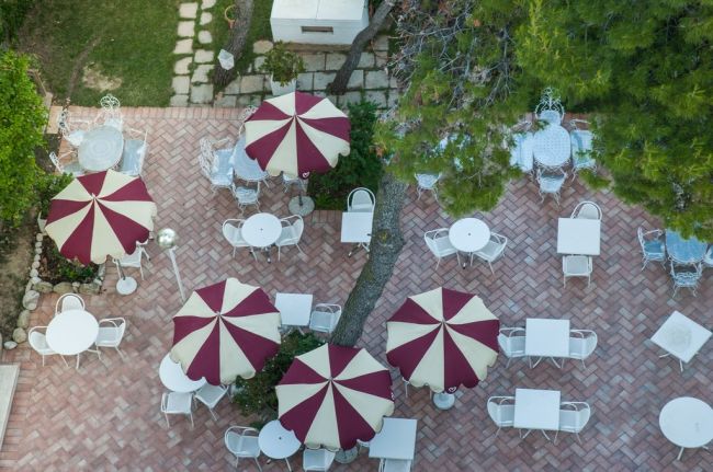 Ombrelloni bordeaux e crema su patio piastrellato.