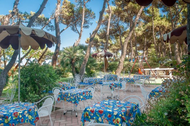 Tavoli all'aperto in un giardino con alberi.