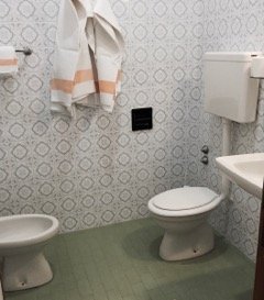 Bagno con piastrelle decorate e sanitari bianchi.