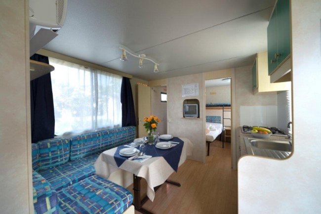 Zona soggiorno con tavolo apparecchiato e cucina.