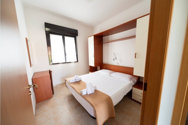 Camera da letto matrimoniale con arredi in legno chiaro.