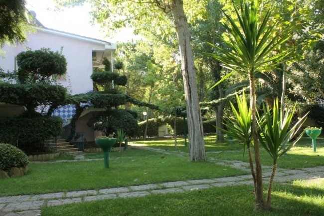 Giardini con alberi e moderne architetture pastello.