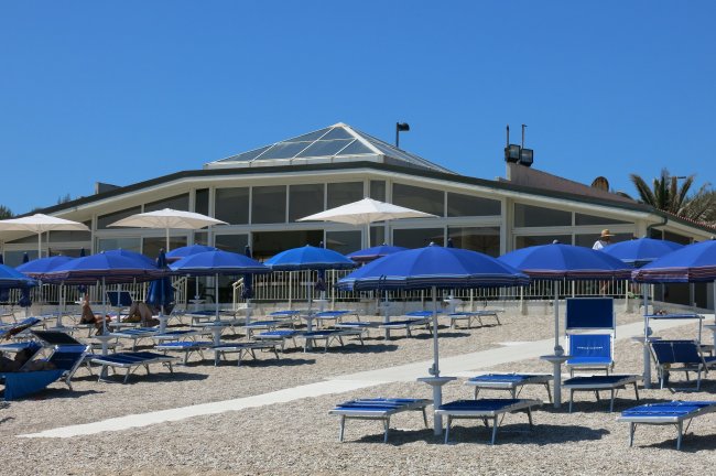Spiaggia con ombrelloni blu e un edificio.