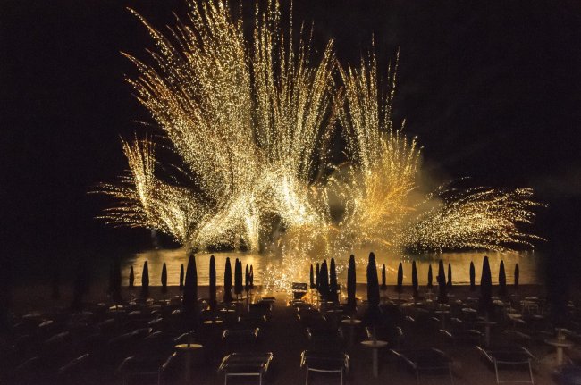 Fuochi d'artificio dorati sopra il mare di notte.