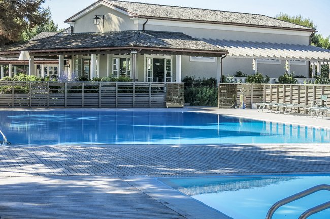 Piscina azzurra con casa sullo sfondo.