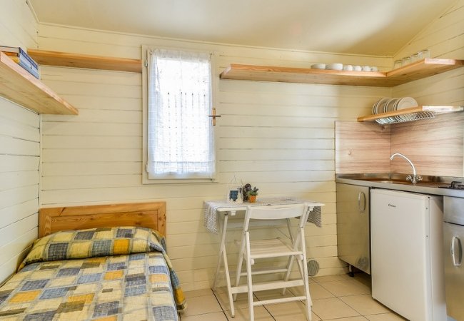 Interno con letto singolo, tavolo e angolo cottura.