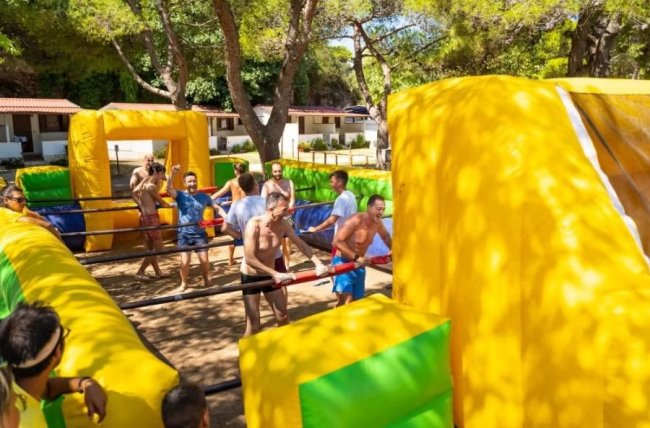Partita di calcio balilla umano all'aperto con partecipanti sorridenti.