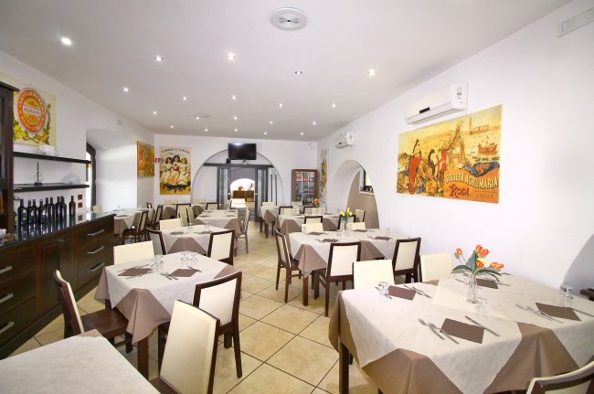 Sala da pranzo con tavoli apparecchiati.