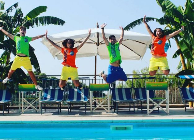 Quattro persone saltano vicino a una piscina.