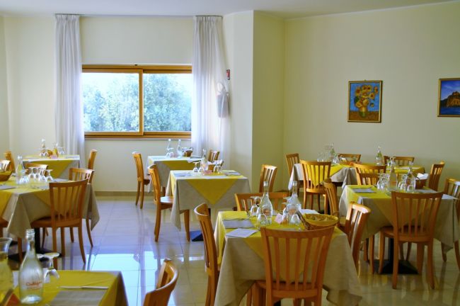 Sala da pranzo con tavoli apparecchiati.