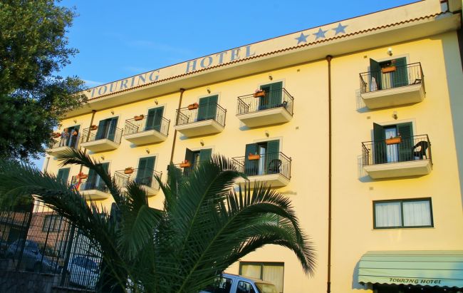 Facciata di un hotel con balconi e palme.