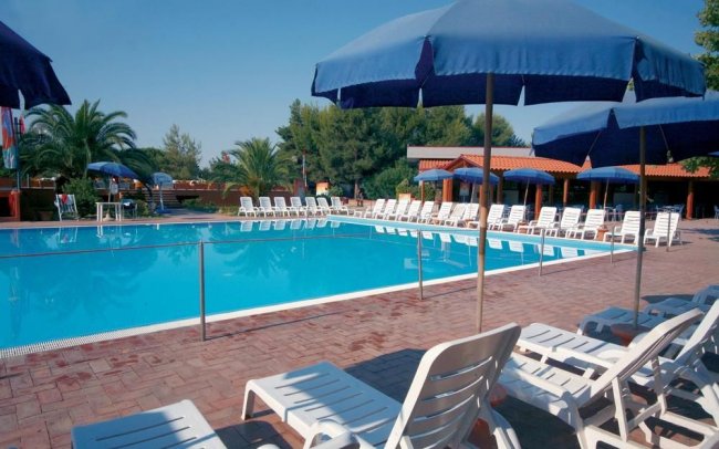 Piscina con lettini e ombrelloni blu.