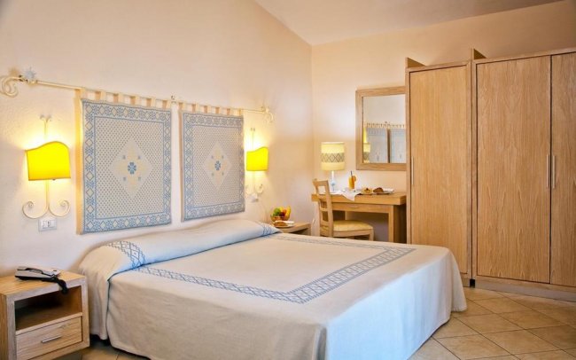 Camera da letto con letto matrimoniale e arredi in legno chiaro.